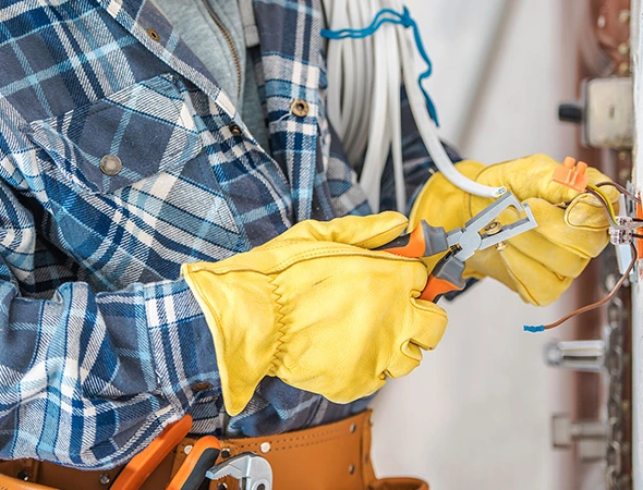 Electrician in yellow safety gloves performing professional electrical services with precision and safety.