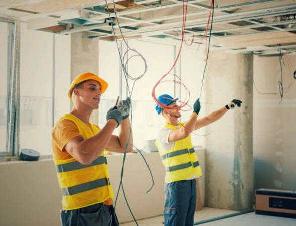 Two technicians performing room wiring with precise load capacity assessment for safe and efficient electrical setup.
