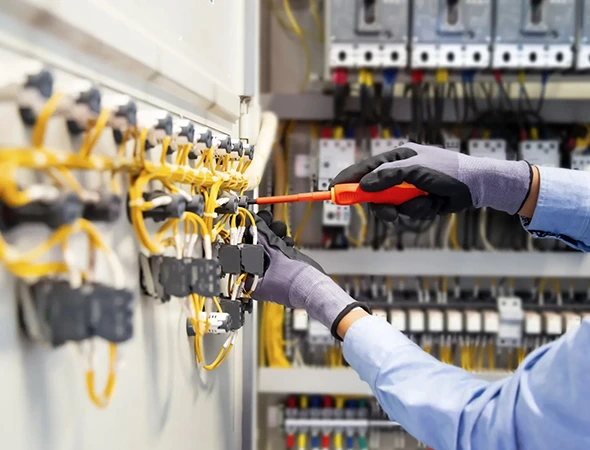 Technician wearing safety gloves performing electrical repairs and maintenance using a screwdriver for safe installation.