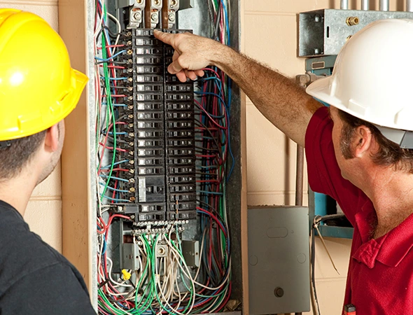 Two technicians carefully inspecting a circuit board to perform accurate and reliable circuit breaker repair.