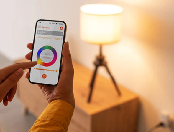 Hand holding smartphone controlling LED system with options to adjust light colors and shades for customized home lighting.